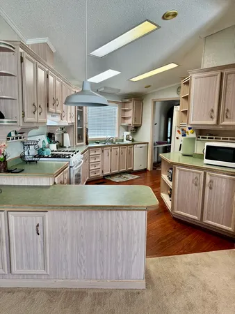a large kitchen with kitchen island a large counter top stainless steel appliances and cabinets