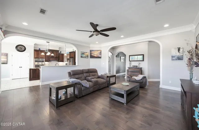 a living room with furniture a ceiling fan and a large window