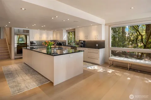 a kitchen with kitchen island a large counter top space a sink stainless steel appliances and windows