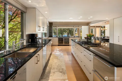 a large kitchen with kitchen island granite countertop a large window and stainless steel appliances