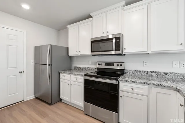a kitchen with cabinets stainless steel appliances and wooden floor