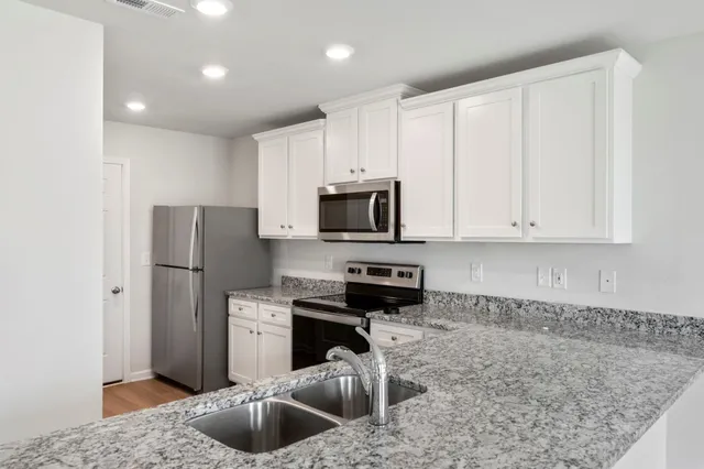 a kitchen with stainless steel appliances granite countertop a refrigerator a stove a sink and a granite counter tops