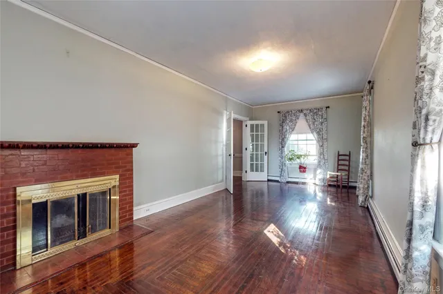 a view of empty room with wooden floor and fireplace