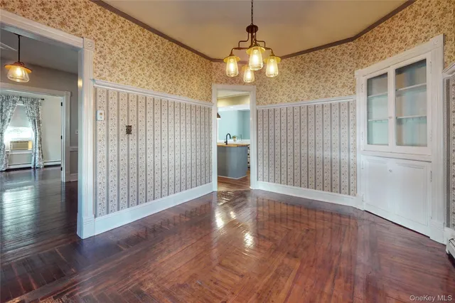 a view of a hallway with wooden floor and chandelier