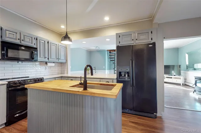 a kitchen with stainless steel appliances granite countertop a refrigerator a stove and a sink with wooden floor