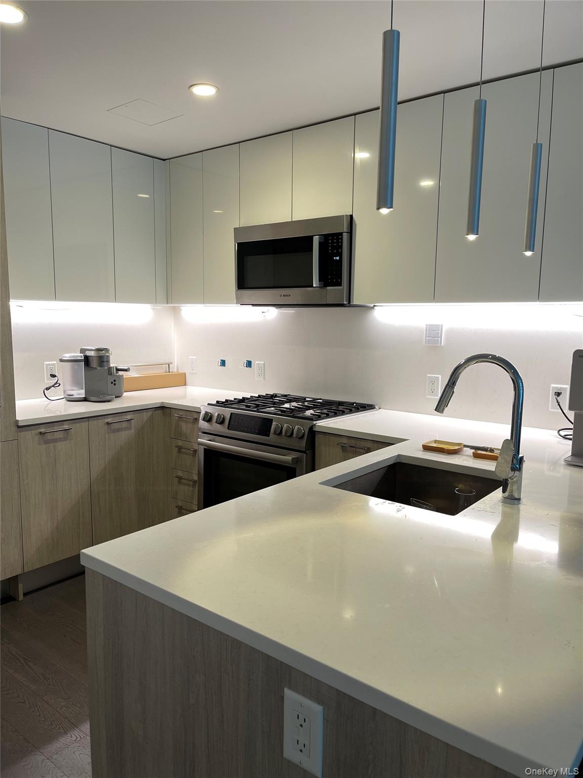 131-05 40 Road, Unit 15M Queens, NY 11354 - Photo 12 of 14 a kitchen with stainless steel appliances a sink a stove a microwave a sink a refrigerator and cabinets