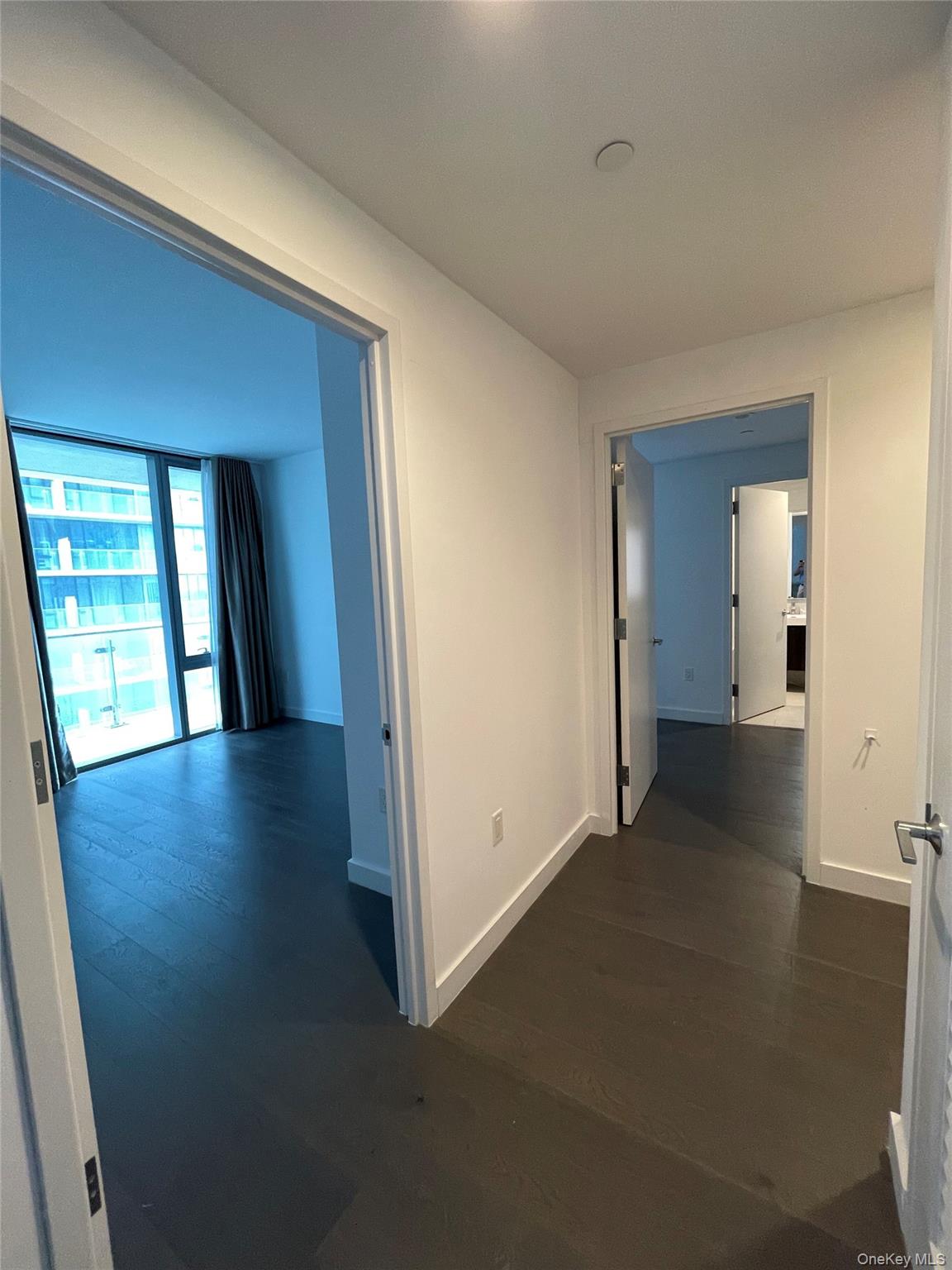 131-05 40 Road, Unit 15M Queens, NY 11354 - Photo 7 of 14 a view of a hallway with wooden floor and a living room