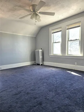 an empty room with chandelier fan and windows