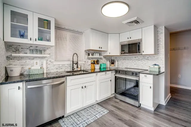a kitchen with stainless steel appliances granite countertop a stove a sink and a microwave