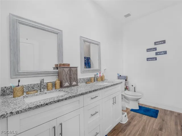 a bathroom with a granite countertop sink mirror and toilet