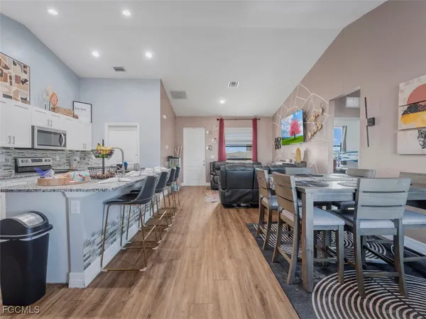 a open kitchen with stainless steel appliances granite countertop a table chairs stove a sink dishwasher and cabinets