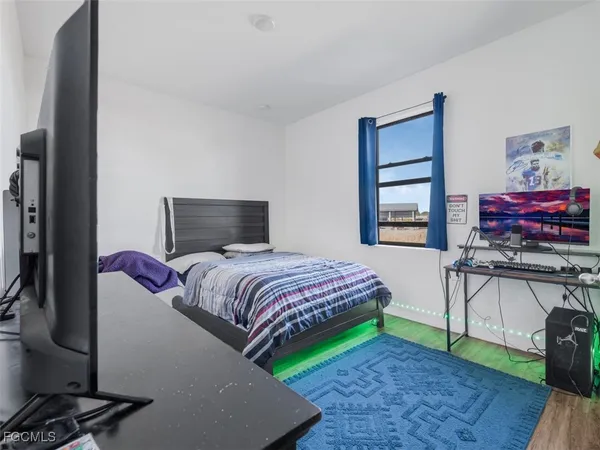a bedroom with a bed and a flat tv screen on dresser