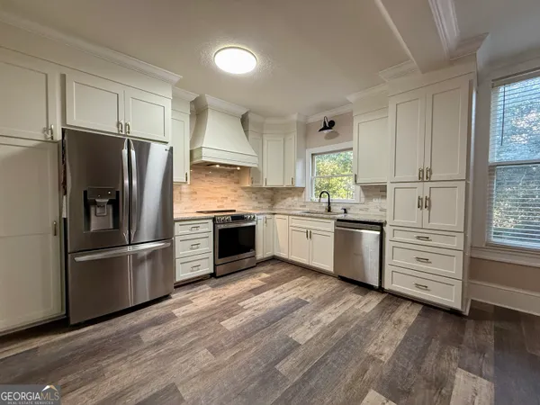 a view of an empty room with wooden floor a ceiling fan and windows