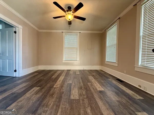 a view of an empty room with wooden floor fireplace and a window