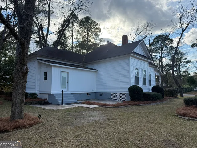a backyard of a house with barbeque oven and a tree