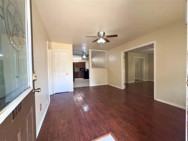 a view of a hallway with wooden floor and a kitchen