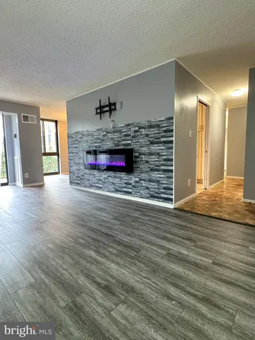 a view of an empty room with wooden floor and a fireplace