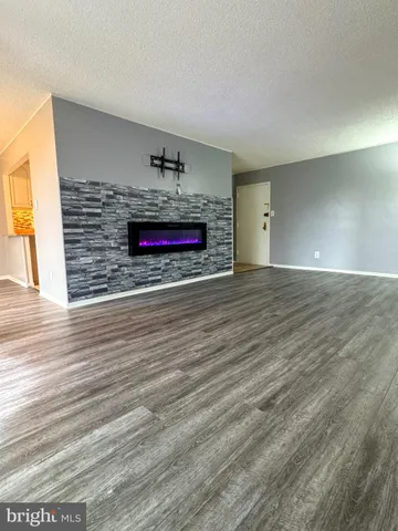 a view of an empty room with wooden floor and a fireplace
