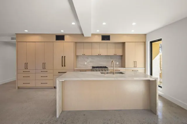 a large kitchen with stainless steel appliances granite countertop a stove a sink a refrigerator and white cabinets