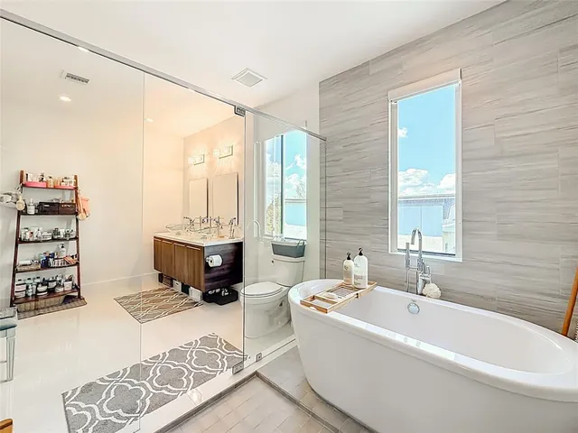 a spacious bathroom with a tub double sink and a mirror