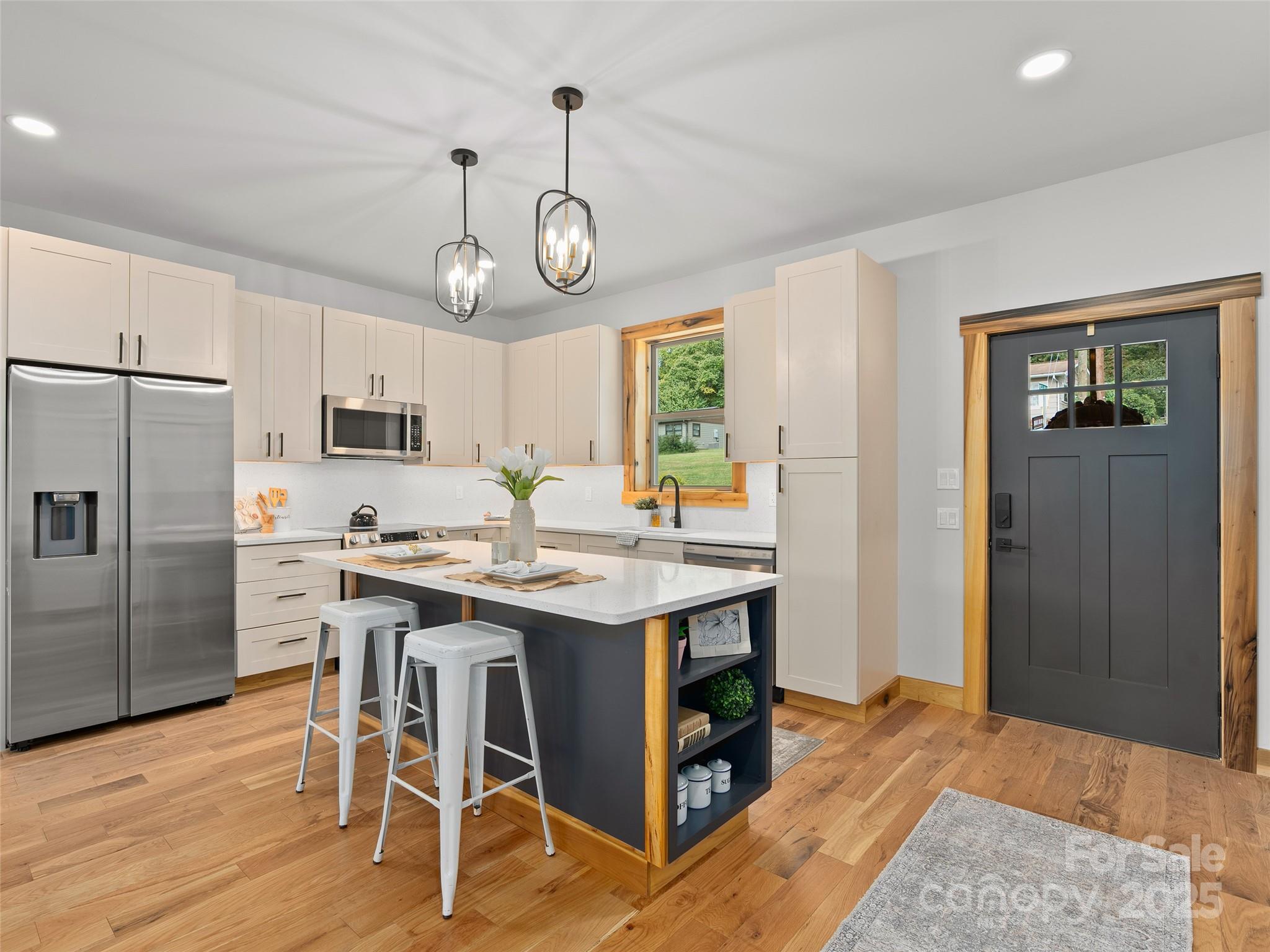 a kitchen with stainless steel appliances kitchen island granite countertop a table chairs refrigerator and microwave