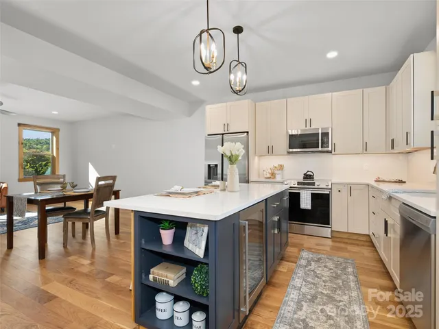 a kitchen with kitchen island granite countertop a stove a sink a dining table and chairs with wooden floor