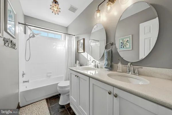 a bathroom with a granite countertop sink mirror toilet and bathtub