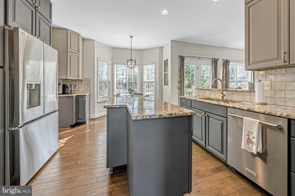 a kitchen with stainless steel appliances granite countertop a refrigerator a stove and a sink