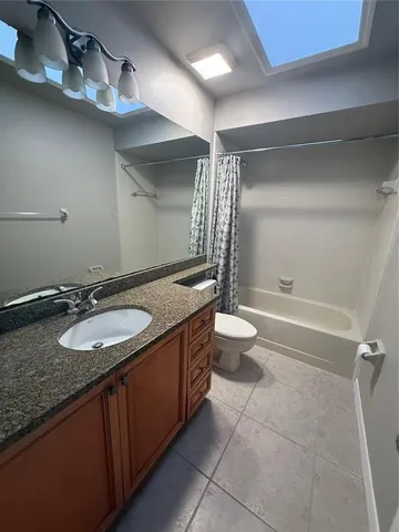 a bathroom with a granite countertop sink a toilet a mirror and shower