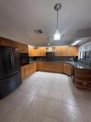 a large kitchen with granite countertop a stove a sink and a refrigerator