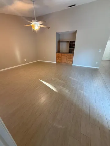 an empty room with wooden floor fan and window
