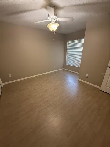 an empty room with windows and ceiling fan