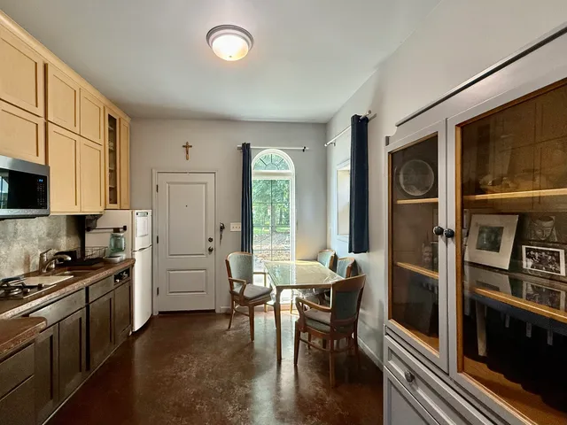 a kitchen with stainless steel appliances granite countertop a refrigerator a stove and a dining table with wooden floor