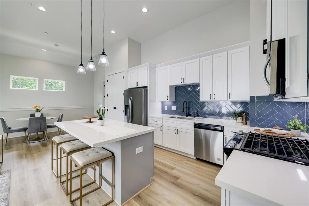 846 Elkhart Street, Unit E Houston, TX 77091 - Photo 4 of 24 a kitchen with stainless steel appliances a stove a sink a refrigerator white cabinets and wooden floor