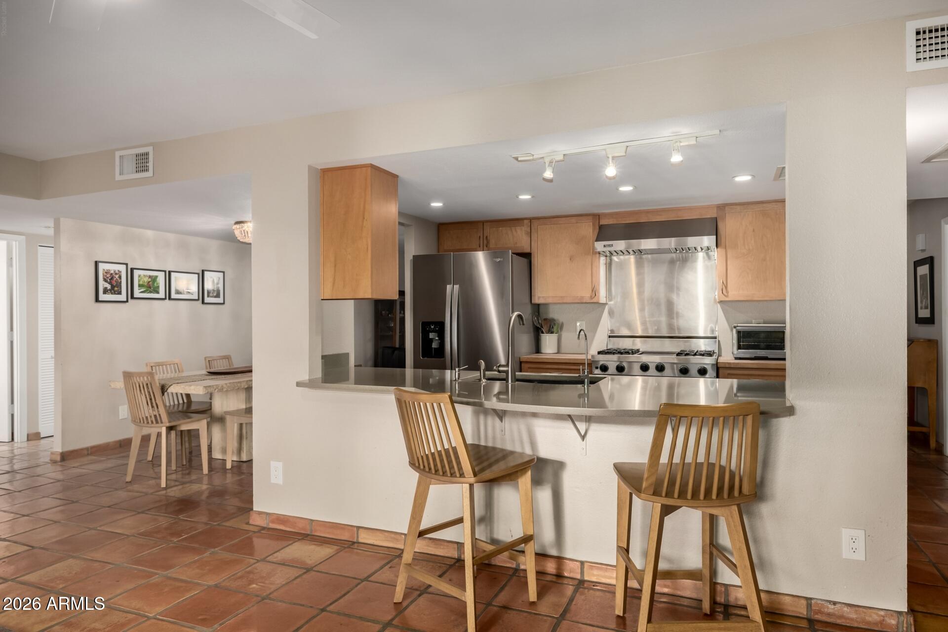 7657 North 22nd Street Phoenix, AZ 85020 - Photo 20 of 76 a kitchen with stainless steel appliances kitchen island granite countertop a dining table chairs and a refrigerator