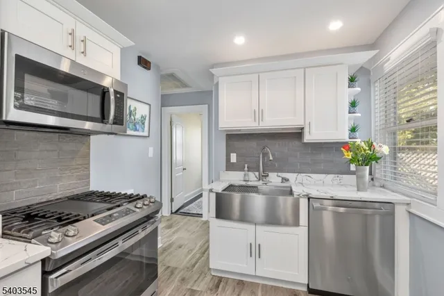 a kitchen with stainless steel appliances granite countertop a stove a sink and a microwave