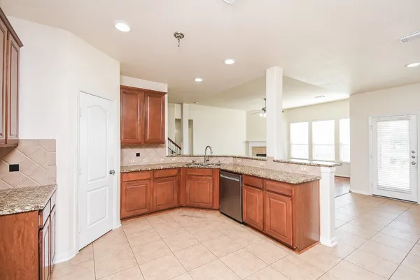 a large kitchen with granite countertop a sink and dishwasher a stove with wooden cabinets