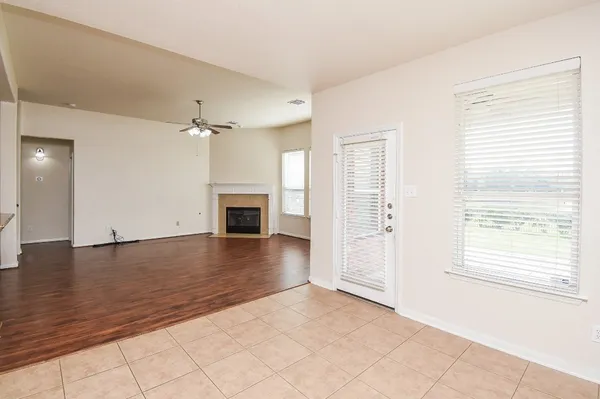 an empty room with wooden floor fireplace and windows