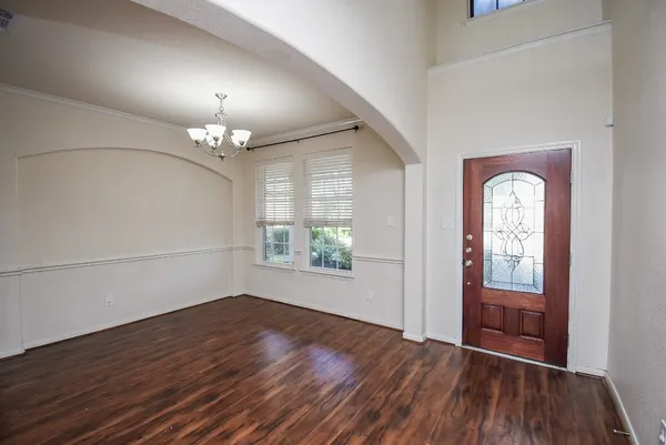 an empty room with wooden floor chandelier and glass door