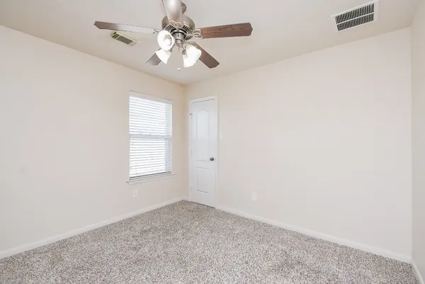 a view of empty room with window and ceiling fan