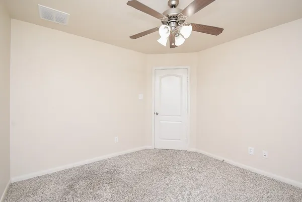 an empty room with a chandelier fan and closet
