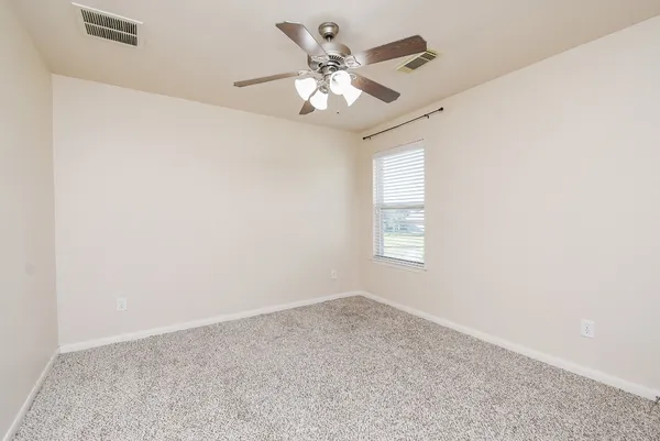 an empty room with a window and a fan