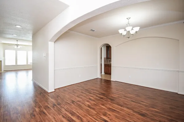 an empty room with wooden floor and chandelier