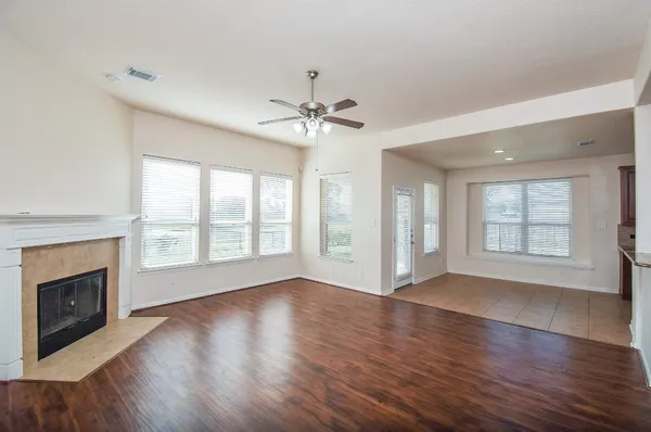 an empty room with wooden floor fireplace and windows