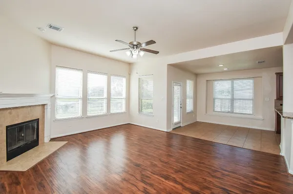 a view of an empty room with wooden floor and a window