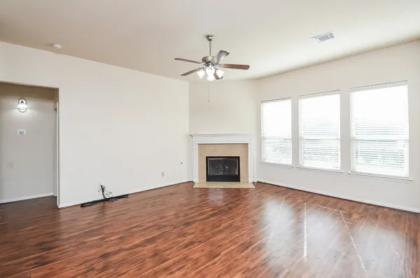 wooden floor fireplace and windows in an empty room
