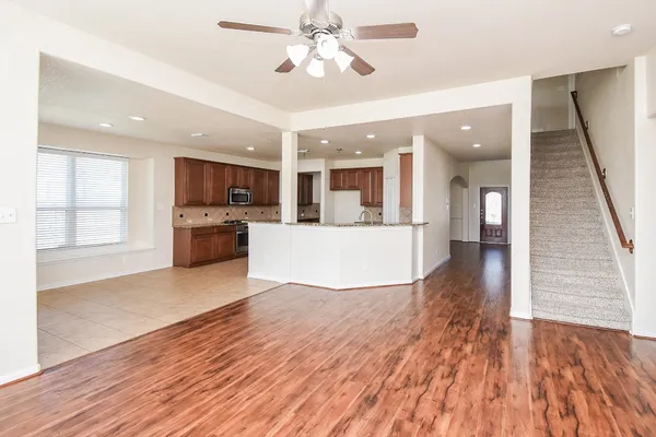 a view of a electric appliances in kitchen and empty room with wooden floor