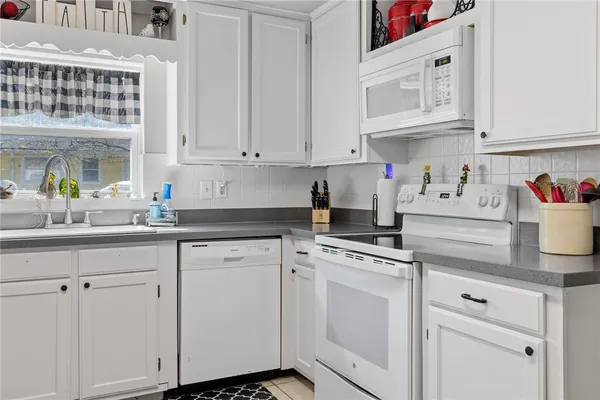 a kitchen with white cabinets and white appliances