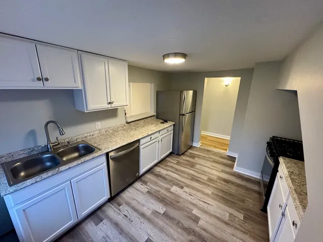 a kitchen with granite countertop white cabinets and stainless steel appliances