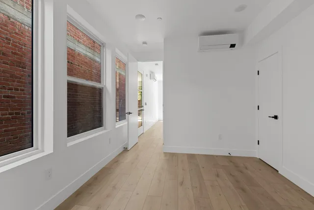 a view of a hallway with wooden floor and a bathroom
